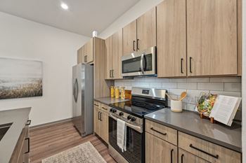 A kitchen with wooden cabinets and stainless steel appliances. at The Concord Luxury Apartments, Florida